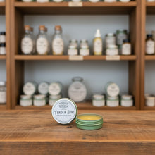 Load image into Gallery viewer, Healing Leaf Apothecary Tender Bum hemorrhoid balm displayed with handcrafted herbal salves in apothecary setting