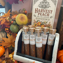 Load image into Gallery viewer, A set of small glass spice tubes with cork stoppers and white labels reading Pumpkin Spice, displayed in a white wooden holder. A large decorative sign behind them says Healing Leaf Apothecary Harvest Peach, surrounded by fall leaves, peaches, cinnamon sticks, and other autumn decor.