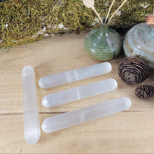 Load image into Gallery viewer, Four clear crystal wand-like tools arranged on a light wood surface, styled with moss, small vases, dried flowers, and pinecones in the background.