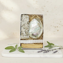 Load image into Gallery viewer, Box containing a shell, white sticks, and wooden tools on a white background