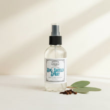 Load image into Gallery viewer, A clear glass spray bottle labeled 'Outdoor Bug Shield Spray' with a black spray top and white label, sitting on a rustic wooden surface against an ivory background.
