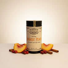 Load image into Gallery viewer, can of harvest peach tea on white a=backdrop surrounded by peaches, rosehips, and cinnamon sticks
