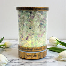 Load image into Gallery viewer, A decorative lamp with a wooden base and glass container filled with multicolored stones, surrounded by white tulips on a marble surface.
