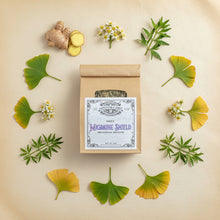 Load image into Gallery viewer, A kraft paper pouch labeled 'Migraine Shield' with a clear window showing dried herbs inside, in mandala of herb ingredients.
