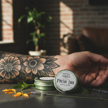 Load image into Gallery viewer, Person displaying Fresh Ink herbal tattoo salve as part of a natural body care routine
