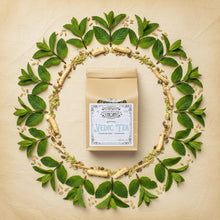 Load image into Gallery viewer, A kraft paper stand-up pouch of Vedic Tea with a white vintage-style label on the front, photographed against a plain parchment background surrounded by fresh green leaf mandala
